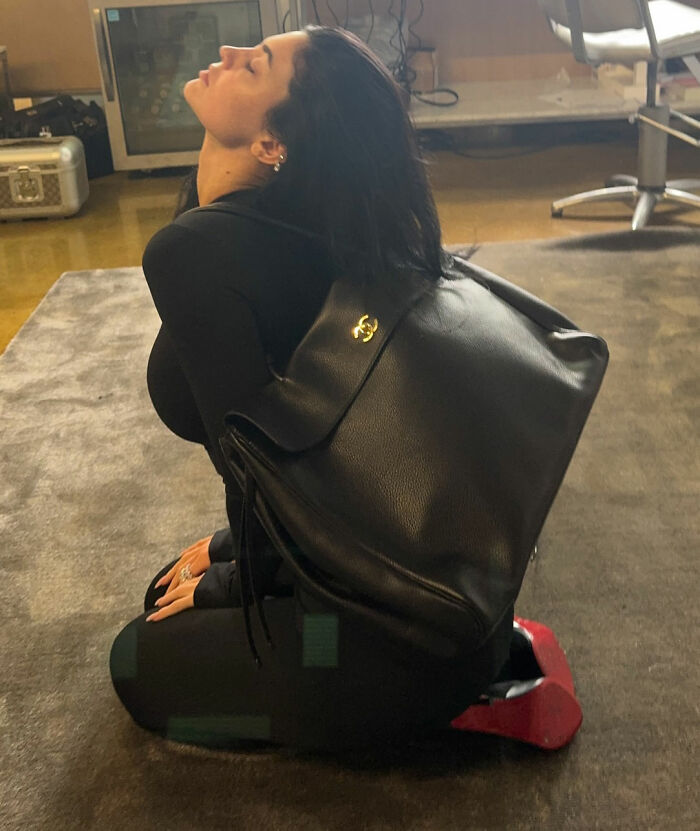 Woman in black outfit with large black leather backpack, highlighting Timothée Chalamet red carpet look odd detail. Woman in black outfit with large black leather backpack, highlighting Timothée Chalamet red carpet look odd detail.