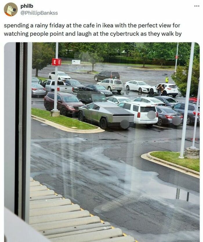 View from a rainy cafe at IKEA parking lot with people laughing and pointing at the Cybertruck parked among other cars.