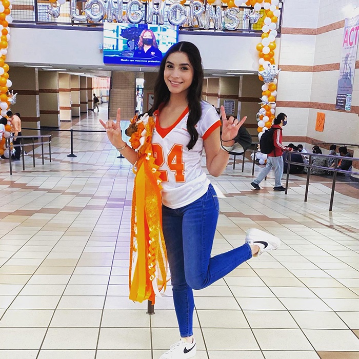 Young cheerleader posing in school hallway with orange ribbons and wearing number 24 jersey related to cheerleader phone clue case Young cheerleader posing in school hallway with orange ribbons and wearing number 24 jersey related to cheerleader phone clue case