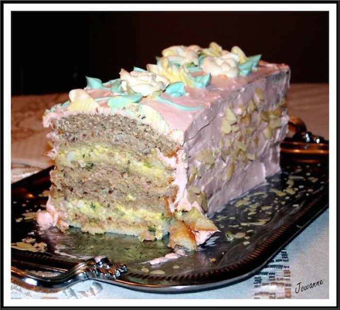 Partially eaten layered cake with pink frosting and decorative icing on a serving tray, a food pic that deserves to be shamed.