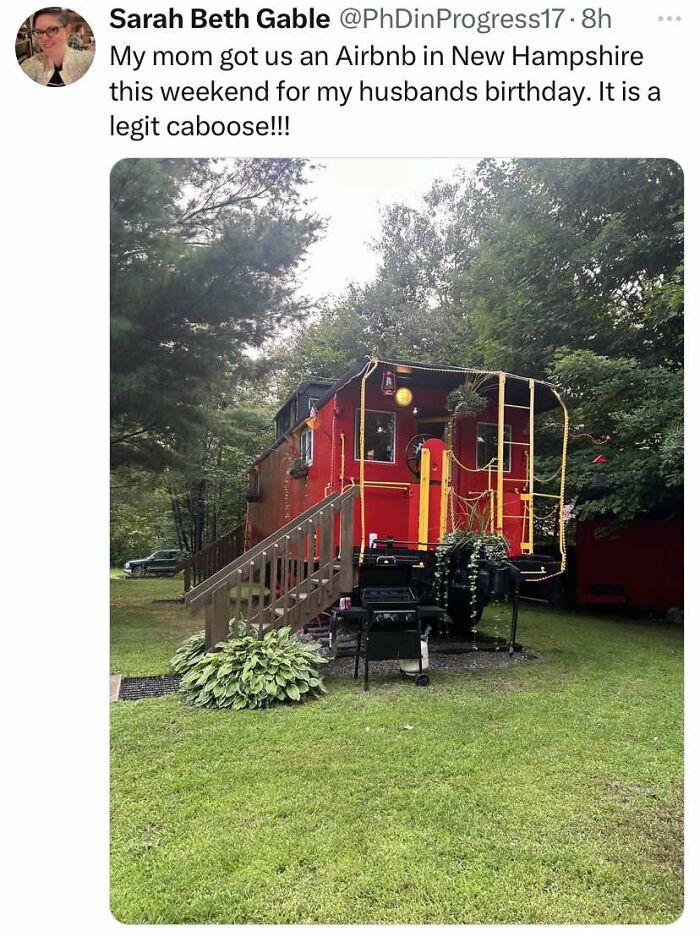 Red caboose converted into Airbnb rental with stairs and outdoor grill, surrounded by trees and green lawn, cheerful meme.