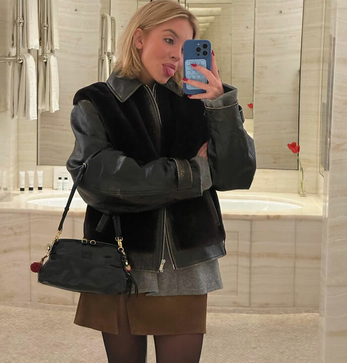 Sydney Sweeney taking a mirror selfie indoors, wearing a black leather jacket and holding a small black handbag. Sydney Sweeney taking a mirror selfie indoors, wearing a black leather jacket and holding a small black handbag.