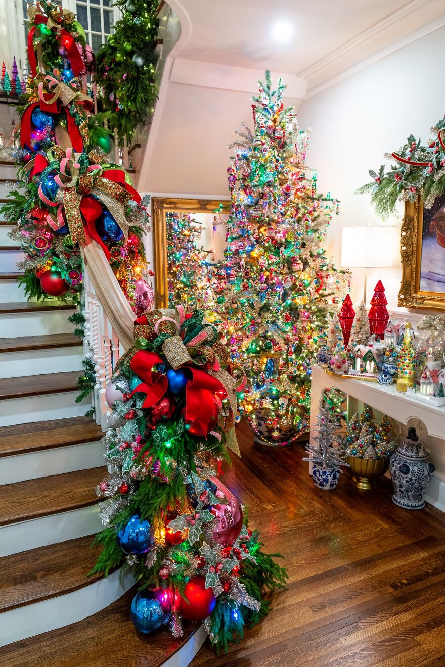Festive vintage Christmas decorations with colorful lights, ornaments, and garlands on staircase and tree in cozy home interior.