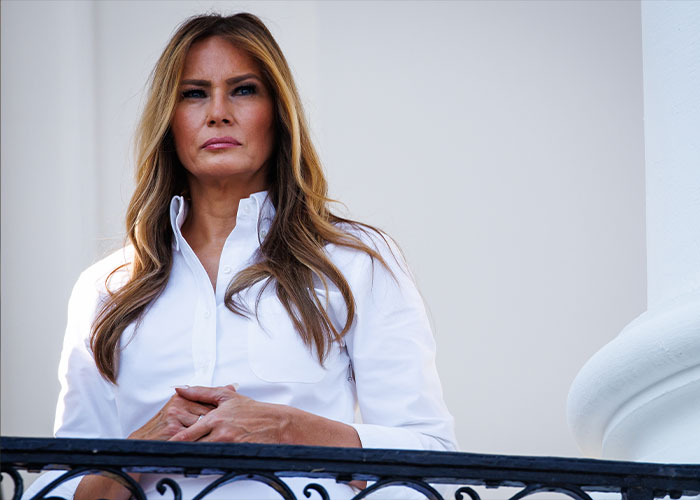 Melania Trump standing on a balcony wearing a white shirt, related to discussions about her new documentary. Melania Trump standing on a balcony wearing a white shirt, related to discussions about her new documentary.