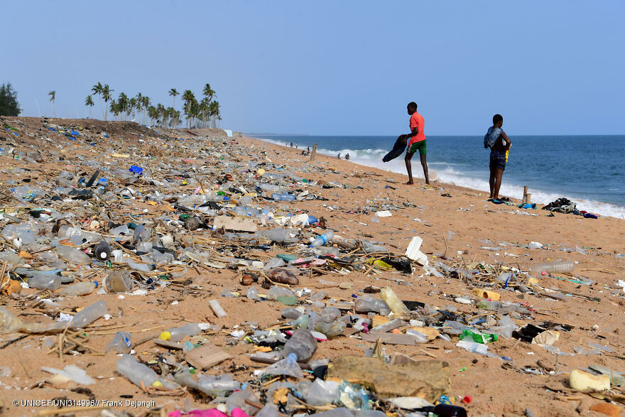 Beach covered in plastic waste and pollution with two people standing near the water, illustrating dirtiest countries pollution impact. Beach covered in plastic waste and pollution with two people standing near the water, illustrating dirtiest countries pollution impact.