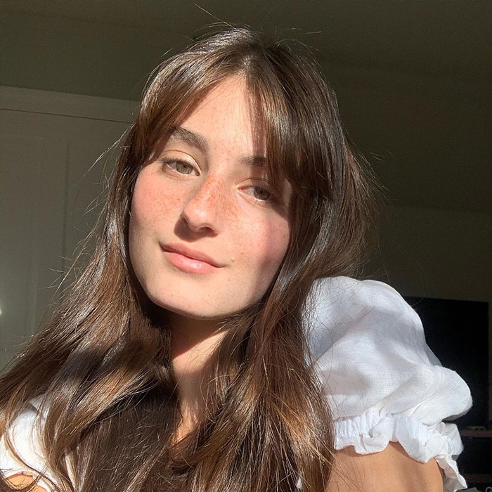 Young woman with long brown hair and freckles, softly smiling in natural sunlight, unrelated to Rob Reiner’s son arrest news. Young woman with long brown hair and freckles, softly smiling in natural sunlight, unrelated to Rob Reiner’s son arrest news.