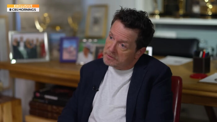 Man in a navy blazer and white shirt sitting in an office, part of a CBS Mornings exclusive on celebrities people think suffer.
