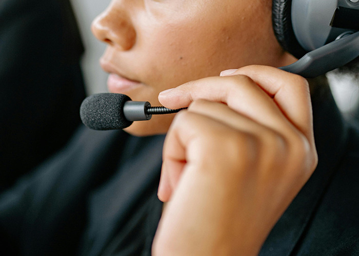 Close-up of 911 operator wearing headset and holding microphone, handling non-emergency calls with focus.