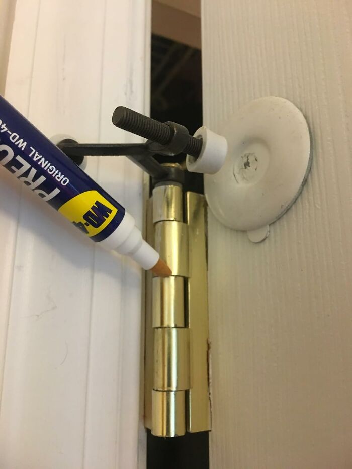 Door hinge being colored with a WD-40 marker as a useful present for home maintenance and repairs.