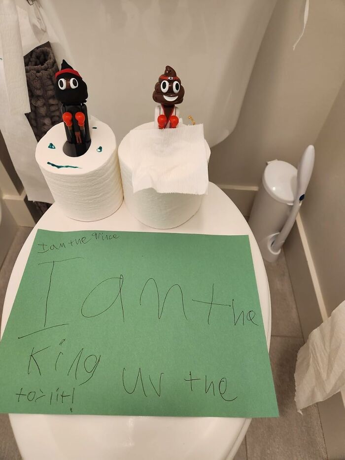 Toilet paper rolls with p**p emoji and black figure gag gifts on top, next to a handwritten note on green paper.