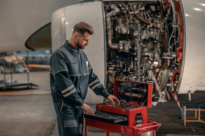 Aircraft mechanic inspecting tools near airplane engine, revealing dark, dirty truths about their industries usually hidden.