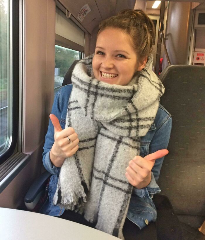 Young woman giving thumbs up on a train, representing confidence in making leap of faith life decisions.
