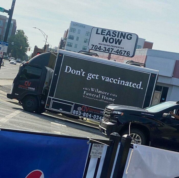 Funny funeral home truck with a "Don't get vaccinated" message driving in a busy city street, showing posts that make you laugh.