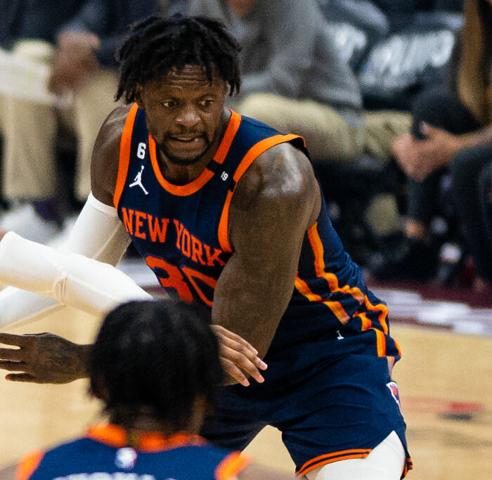 Julius Randle playing basketball in New York Knicks uniform during an intense game on the court.