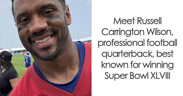 Russell Wilson smiling on a football field during practice, wearing a red jersey and black eye paint.