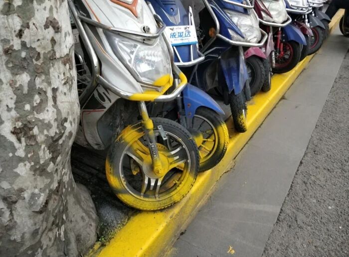Motorbikes parked against a yellow curb with tire paint marks, showing an example of poor job e*******n.
