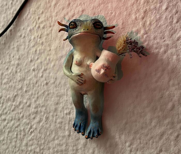 Unique handmade sculpture of a creature holding a vase with dried flowers, showcasing cool creative art people made and shared.