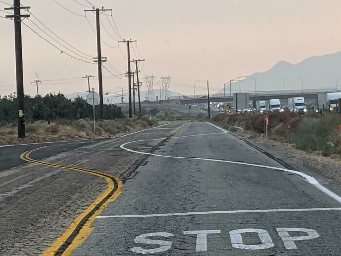 Road with poorly done and confusing painted lines and stop sign markings showing job fails.