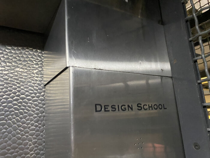 Metal sign with misaligned letters reading Design School, showing poor job e*******n almost impressive work fail.
