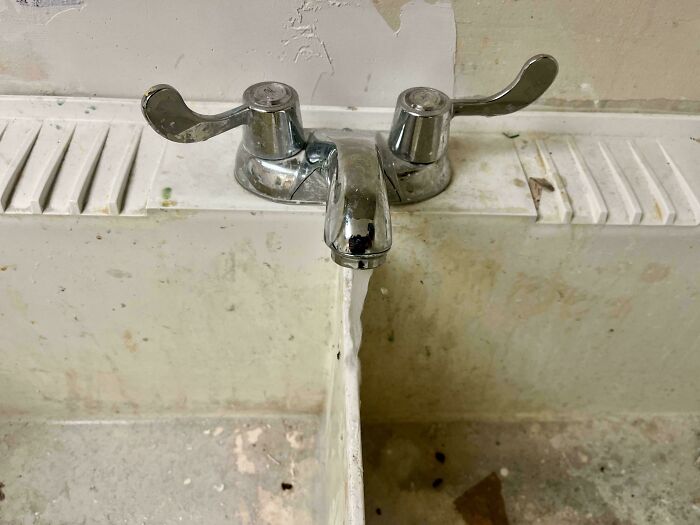 Poorly done plumbing faucet installed between two sinks showing impressive job failure and bad workmanship.
