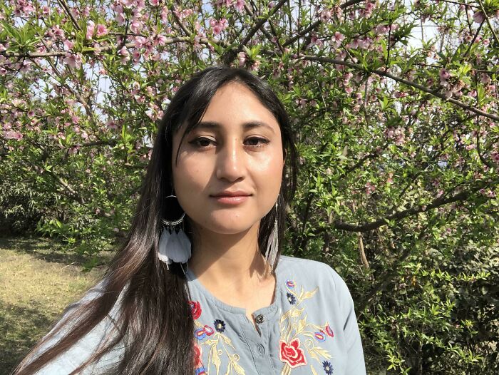 Young woman outside by blooming trees, embracing a leap of faith and making a positive life decision.