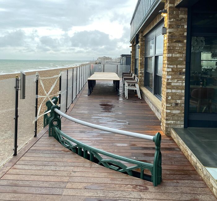 Outdoor deck at beach with a poorly executed railing installation creating a hazardous gap on the wooden floor surface.