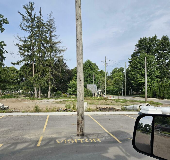 Parking space labeled visitor with a large wooden pole blocking the entire spot, showing poor job e*******n.