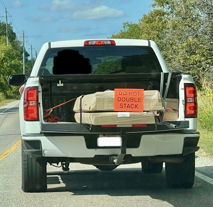 Pickup truck carrying double-stacked packages with a visible sign ignoring job instructions, showing poor job performance.