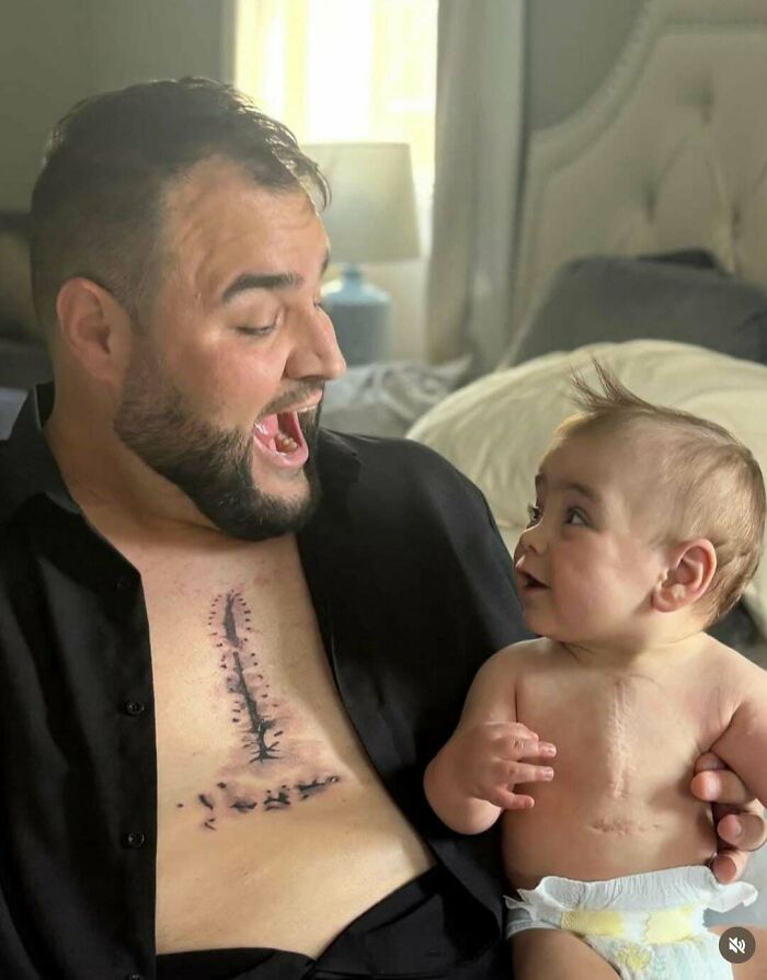 Man with a meaningful tattoo on his chest interacting joyfully with a baby, showcasing wholesome tattoos and deep connections.