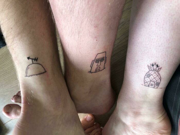 Three simple and wholesome tattoos on ankles featuring a hill with arrow, a face, and a pineapple design. Three simple and wholesome tattoos on ankles featuring a hill with arrow, a face, and a pineapple design.