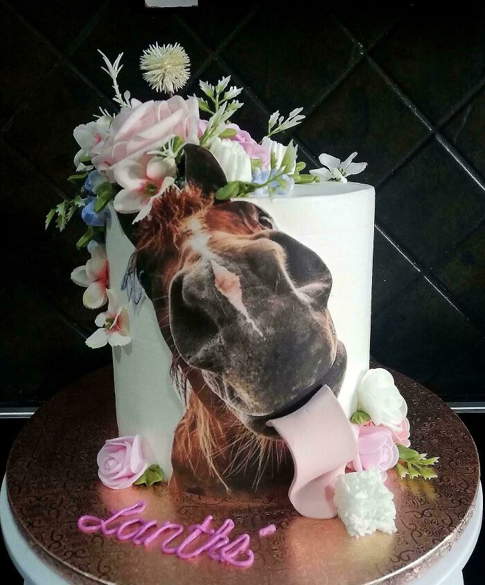 Round cake with a horse image and edible flowers, showcasing masterfully crafted cakes and human creativity in cake design.