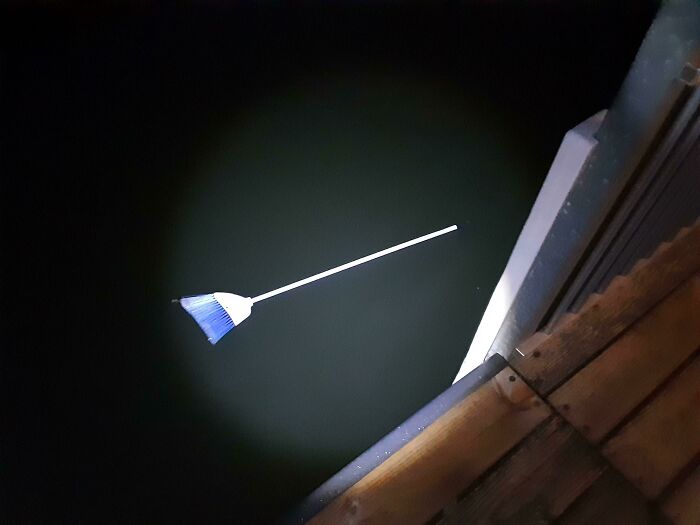 Broom appearing to float above dark water in a confusing photo that tricks the brain for a moment.