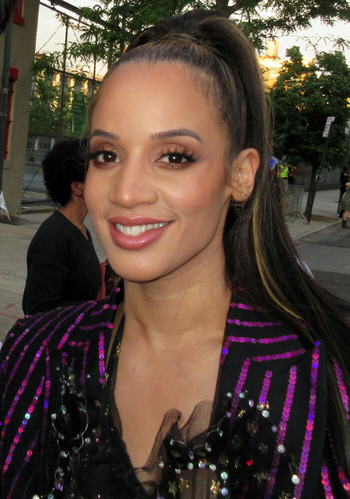 Dascha Polanco smiling outdoors, wearing a sequined jacket with her hair in a high ponytail during an event appearance
