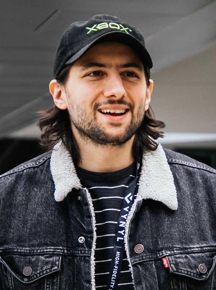 Eric Barone smiling, wearing an Xbox cap and a black denim jacket with a shearling collar in an indoor setting.