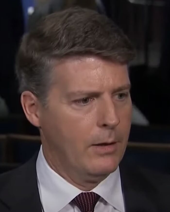 Hal Steinbrenner wearing a suit and tie, speaking during an interview about his bio and career highlights.