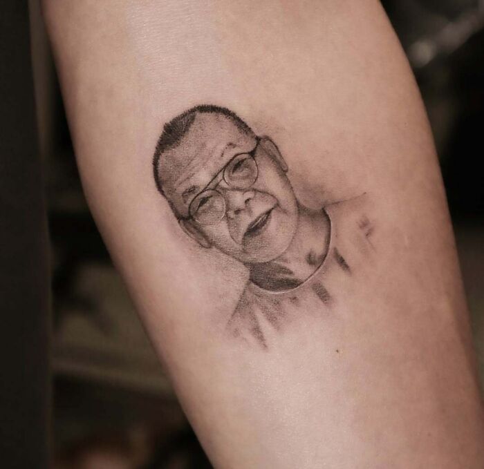 Portrait tattoo of an elderly man wearing glasses on forearm, showcasing wholesome tattoos with meaningful little ink.