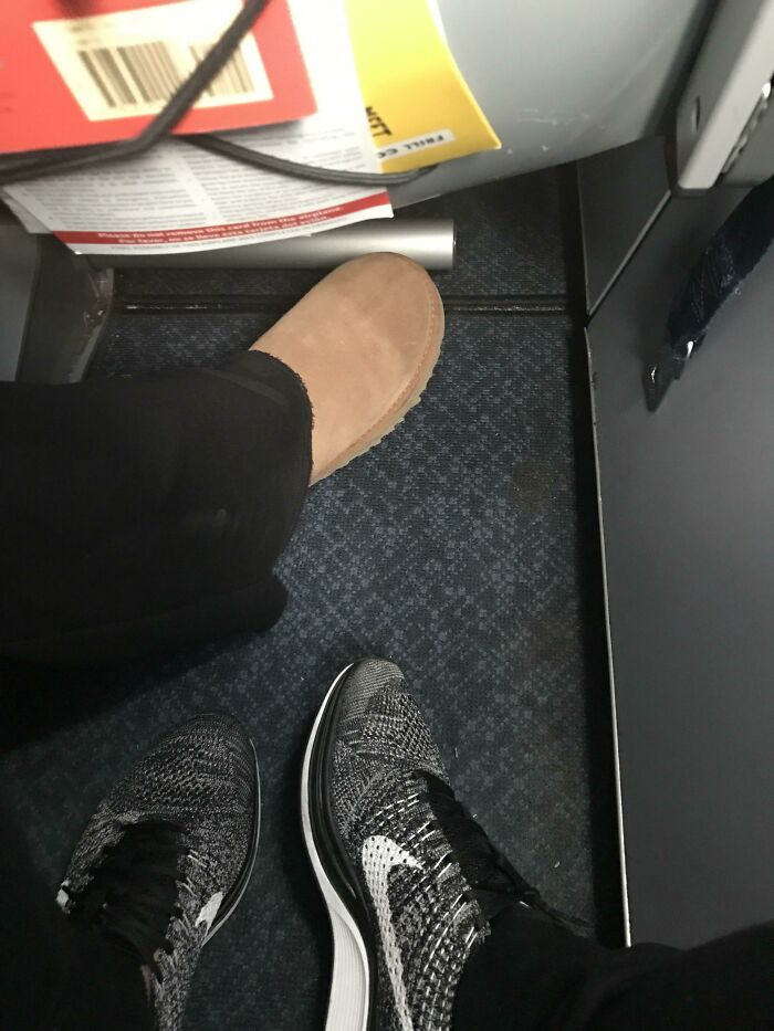 Footwear cramped on airplane floor with one passenger’s shoe blocking legroom, showing a rage-inducing travel annoyance.