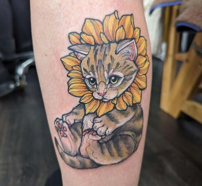 Tattoo of a cute kitten surrounded by sunflower petals inked on forearm, showcasing wholesome tattoos with deep meaning.