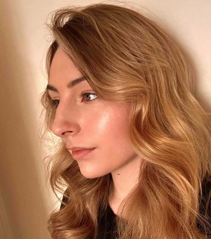 Young woman with wavy blonde hair looking thoughtful, representing people who took a leap of faith in life decisions.