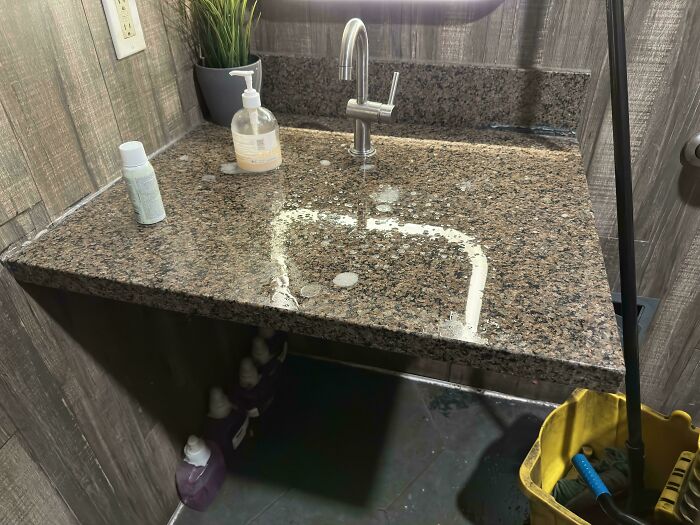 Bathroom sink with water overflowing and pooling on granite countertop causing a rage-inducing mess.