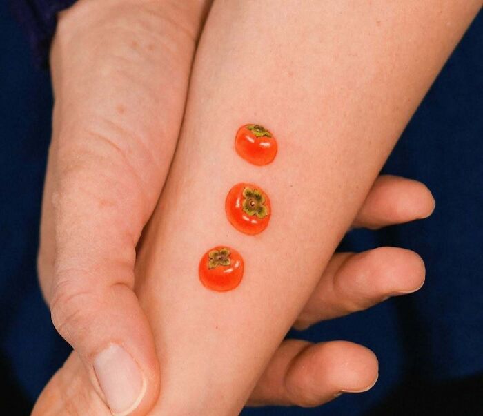 Small wholesome tattoos of three bright orange persimmons on inner forearm, showcasing meaningful ink art. Small wholesome tattoos of three bright orange persimmons on inner forearm, showcasing meaningful ink art.