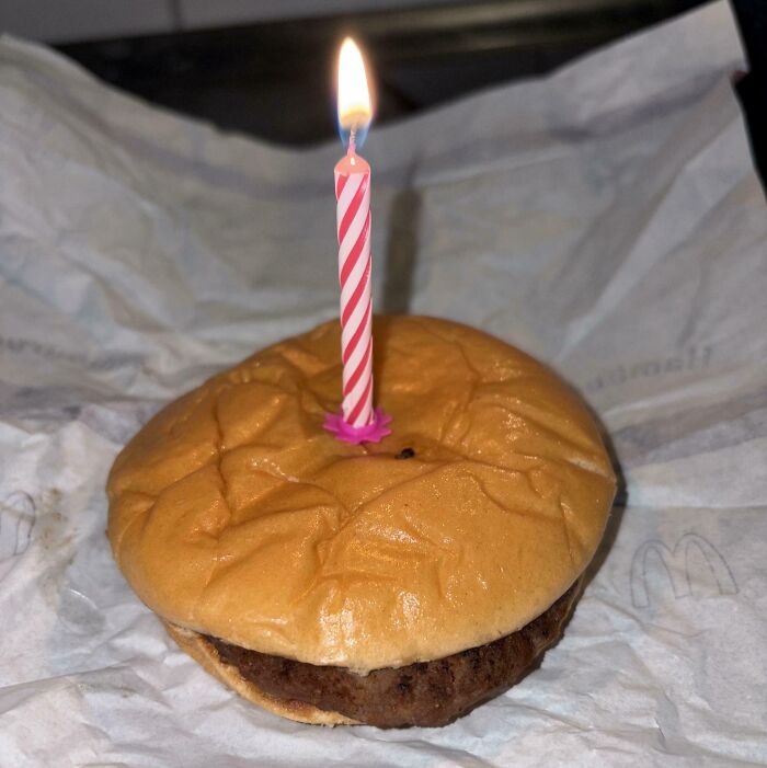 Burger with a lit birthday candle on top symbolizing leap of faith and making bold life decisions.