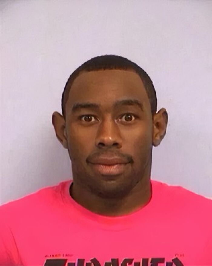 Mugshot of a man in a bright pink shirt, representing infamous celebrity mugshots and reasons for their arrests.