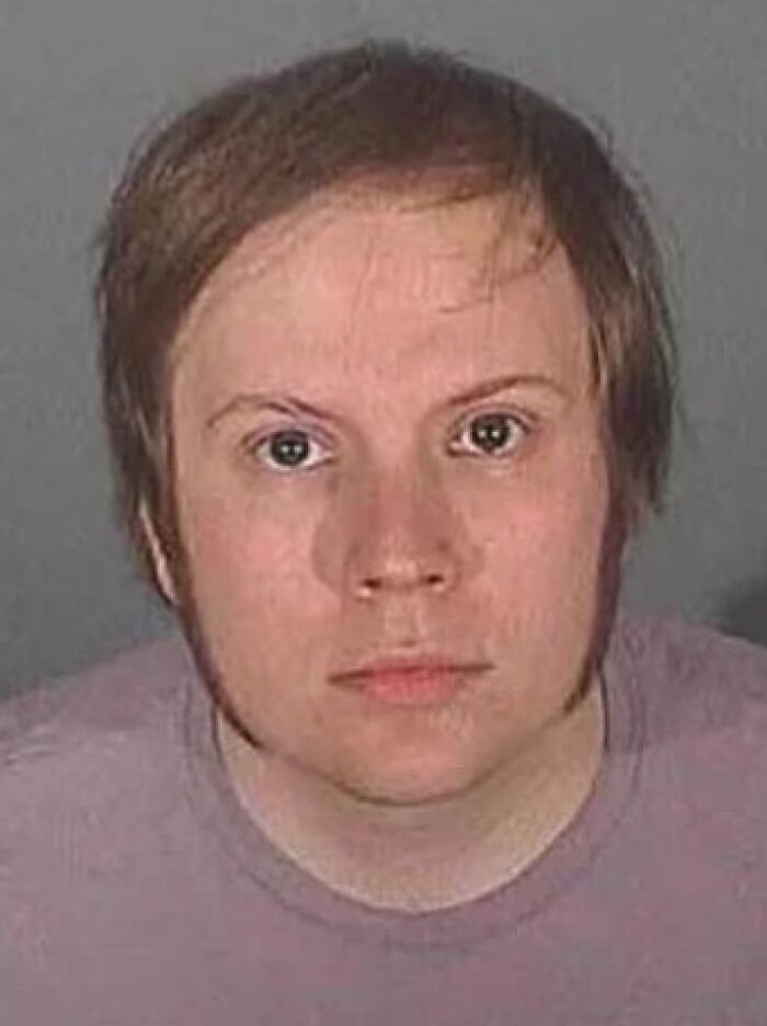Young man in a plain shirt in a close-up infamous celebrity mugshot for reasons they got arrested.