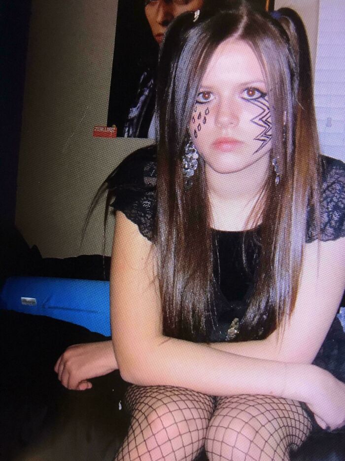 Teen girl with painted face and fishnet stockings sitting with crossed arms, showcasing hilariously awkward childhood photo style.