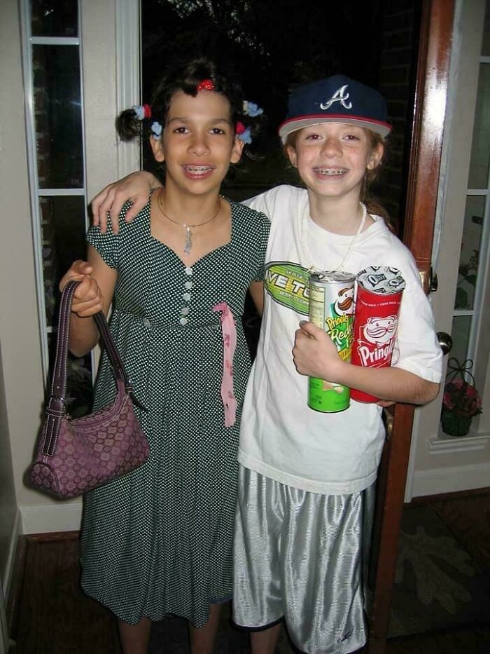 Two kids posing for a photo with braces, one dressed in a dress holding a purse, the other holding Pringles in a hilarious childhood photo.