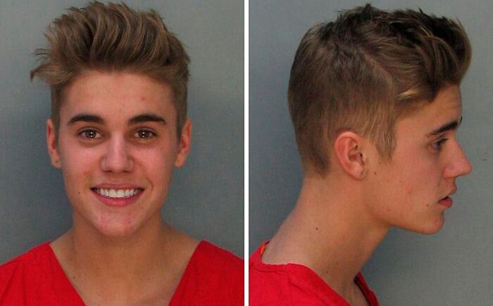 Young male celebrity in a red shirt shown in infamous mugshots related to reasons for getting arrested.