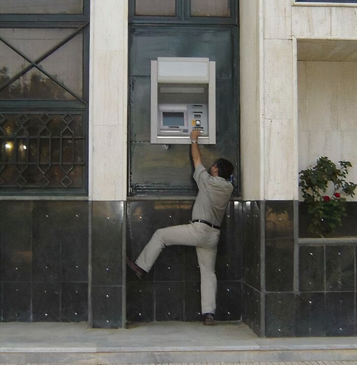 Man struggling to reach an awkwardly placed ATM machine, showing poor job e*******n almost impressive in its failure. Man struggling to reach an awkwardly placed ATM machine, showing poor job e*******n almost impressive in its failure.