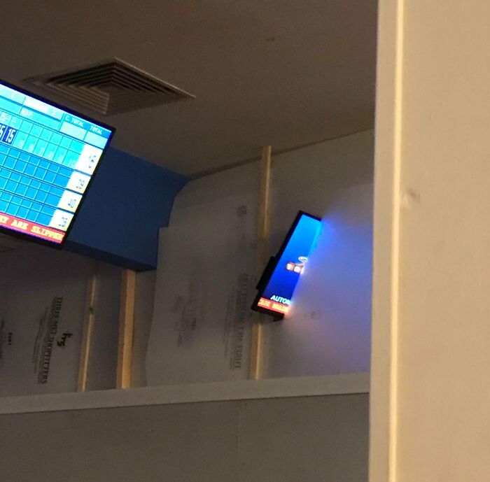 Two screens installed at awkward angles on a wall, showing poor job e*******n in placement and alignment.