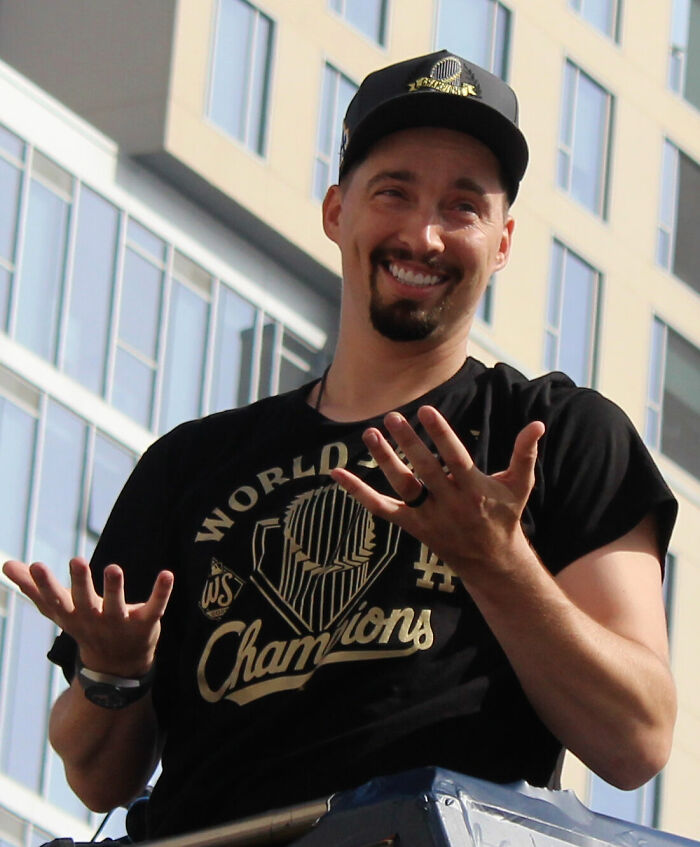 Blake Snell smiling and wearing a World Series Champions hat and shirt during a celebratory event outdoors.